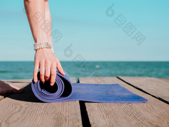 年轻的美丽的运动女人准备瑜伽体式海海滩水女孩覆盖紫色的席健康概念