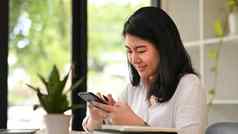 愉快的亚洲女人聊天在线打字文本消息聪明的电话