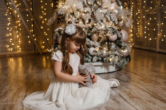 女孩节日光衣服豪华的玩具手圣诞节树灯花环背景概念一年假期