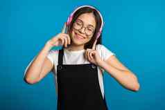 漂亮的年轻的亚洲女孩长头发有趣的微笑跳舞耳机工作室蓝色的背景音乐跳舞广播概念