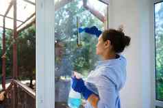 后视图女仆家庭家务清洁窗户删除污渍灰尘条纹保持房子整洁