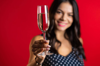 有吸引力的拉丁女人微笑持有玻璃香槟<strong>酒红色</strong>的工作室背景聚会，派对情绪