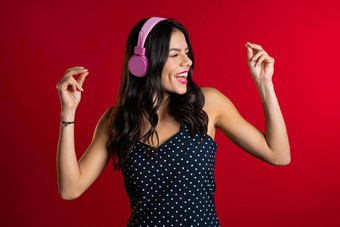 漂亮的年轻的女孩长头发有趣的微笑跳舞粉红色的耳机工作室红色的背景音乐跳舞广播概念