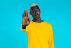 肖像非洲美国男人。显示拒绝手势停止棕榈标志的家伙孤立的蓝色的背景