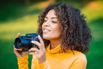 年轻的漂亮的非洲女人黄色的需要图片数码<strong>单反相机</strong>相机绿色背景女孩微笑有趣的摄影师