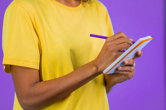 yhands年轻的女人使笔记规划师非洲夫人持有笔写未来计划待办事项列表笔记本周月保持<strong>个人日记</strong>紫色的工作室背景