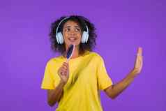 非洲女人唱歌跳舞头发刷梳子麦克风紫色的工作室背景少年耳机有趣的听音乐梦想名人
