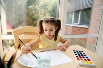 前视图学龄前儿童女孩黄色的t恤马尾辫享受水彩绘画艺术类首页