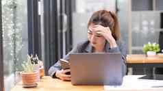 年轻的亚洲女商人办公室桌子上处理智能手机问题接收投诉电子邮件老板