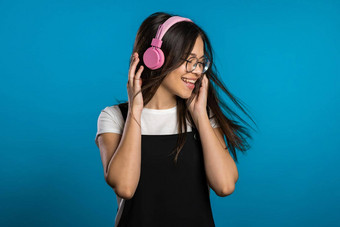 漂亮的年轻的亚洲女孩长头发有趣的微笑跳舞耳机工作室蓝色的背景音乐跳舞广播概念