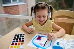 快乐孩子可爱的欧洲女孩学前教育听音乐耳机学习水彩画绘画