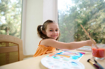 可爱的学龄前儿童女孩微笑相机绘画图片水彩画画笔