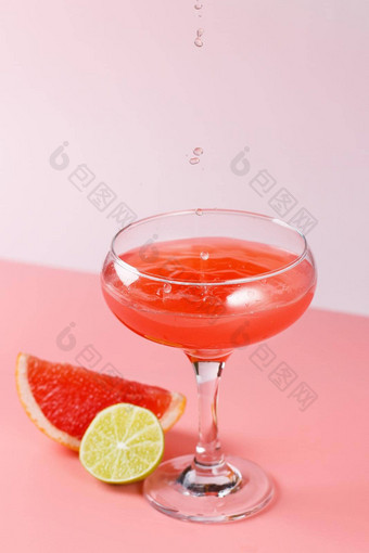 新鲜的葡萄柚汁滴下降玻璃粉红色的背景葡萄柚片石灰粉红色的背景复制空间