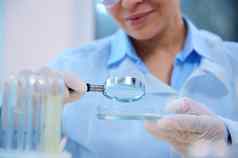 放大镜放大玻璃手女科学家医疗生物学家检查生物材料佩特里菜