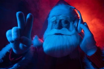圣诞老人老人显示<strong>手指</strong>听音乐耳机聚会，派对蓝色的红色的霓虹<strong>灯</strong>光烟