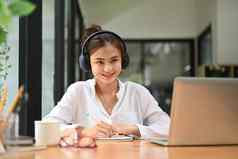 有吸引力的女学生穿耳机听讲座研究在线移动PC教育电子学习距离培训
