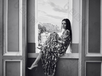 肖像成人美丽的成熟的女人坐着窗口窗台上建筑城市夫人<strong>丝绸衣服</strong>迷人的化妆微笑相机黑色的白色