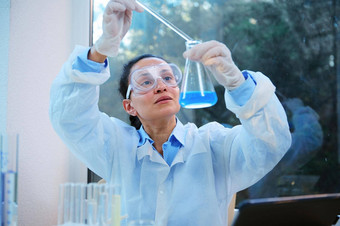 非洲美国女人科学家化学家滴试剂平底的瓶蓝色的化学解决方案
