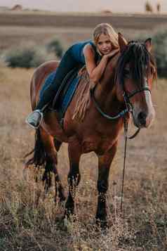漂亮的年轻的女孩坐着马自然背景概念爱友谊农场动物