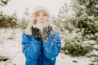 年轻的可爱的女孩吹雪手相机散射国冬天森林背景肖像可爱的女人幼稚地喜乐自然