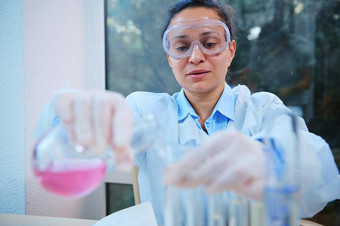 非洲美国女人化学家药理学家倒粉红色的流体物质玻璃实验室瓶测试管