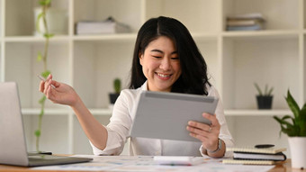 成功的亚洲女人企业家数字平板电脑工作金融文档当代工作场所