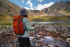 后视图年轻的女人享受山湖旅游距离岩石山峰山夏天假期概念