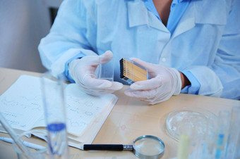 特写镜头科学家化学家手医疗手套持有容器石蕊纸测量