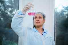 美丽的女人科学家医疗生物学家药理学家实验室外套检查流体物质玻璃瓶