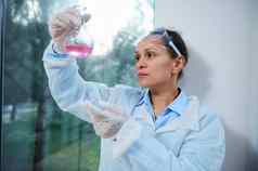 女药理学家检查化学反应实验室玻璃瓶使科学实验临床研究