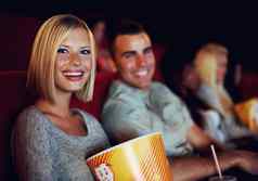电影爆米花微笑女人日期男人。电影室内剧院事件快乐电影显示屏幕夫妇吃零食看晚上时间