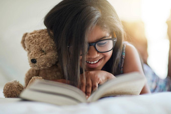 泰迪爱故事时间可爱的女孩阅读书卧室Teddybear一边
