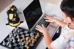 亚洲男孩编程代码机器人机手臂移动PC玩国际象棋