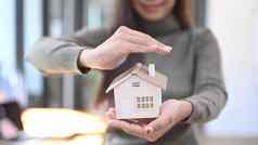 微笑女人持有小房子模型真正的房地产财产保险概念