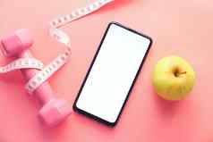健康的饮食概念聪明的电话苹果哑铃粉红色的背景