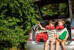 可爱的孩子们男孩坐着车树干离开夏天假期兄弟姐妹兄弟使自拍智能手机快乐家庭长旅程