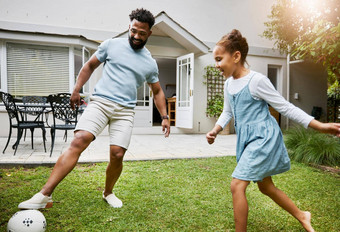 玩成键有趣的花园微笑父亲快乐女孩爸爸教学足球学习显示女儿踢足球球在户外