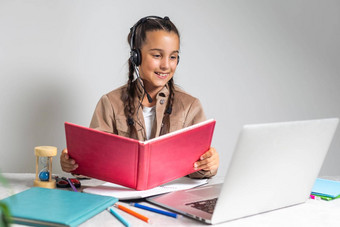 在线教育可爱的女孩研究首页移动PC无线耳机可爱的孩子网络教训老师享受距离学习检疫时间免费的空间
