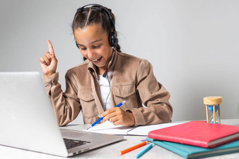 肖像女孩无线耳机移动PC研究在线首页感兴趣快乐学生打字键盘屏幕看网络研讨会在线家庭作业