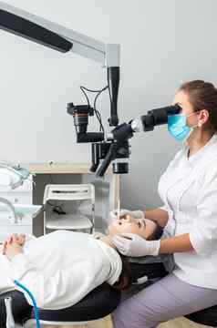 女牙医牙科显微镜治疗病人牙齿牙科诊所办公室医学牙科健康护理概念牙科设备