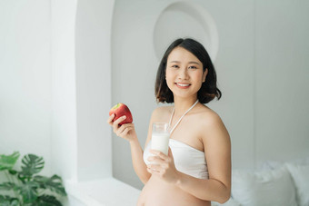 怀孕了亚洲女人持有玻璃<strong>牛奶</strong>红色的苹果<strong>首页</strong>