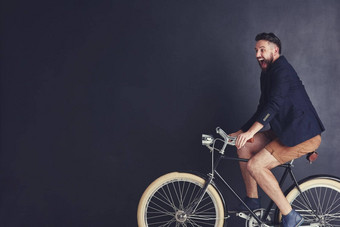 自行车填满天真烂漫的快乐时尚的年轻的男人。骑自行车工作室