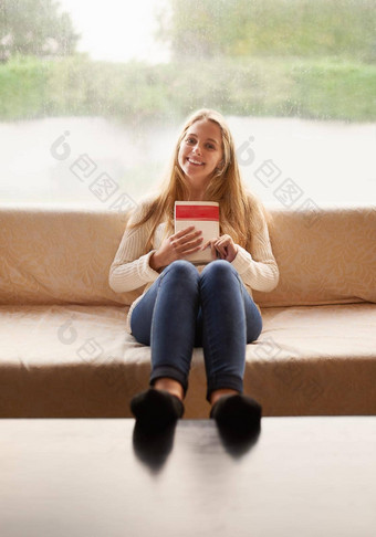 好书肖像有吸引力的年轻的女人持有书坐着沙发首页