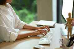 年轻的女商人手打字无线键盘工作电脑当代工作场所