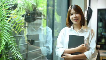 肖像年轻的亚洲女人员工站办公室窗口微笑相机