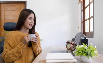美丽的年轻的微笑亚洲女人工作移动PC喝咖啡生活房间首页亚洲业务女人工作文档金融计算器首页办公室享受时间首页
