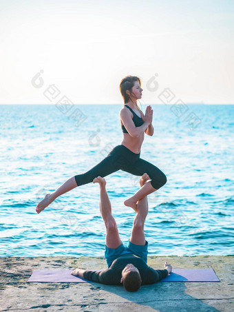 年轻的美丽的夫妇练习<strong>爱人</strong>瑜伽海海滩水男人。女人日常实践户外自然背景健康的生活方式概念