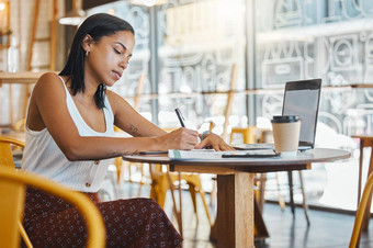 学生写作采取笔记项目赋值咖啡馆餐厅移动PC笔记本年轻的女人采取在线教育类研究工作学习咖啡商店