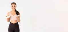 体育运动幸福活跃的生活方式概念微笑苗条的亚洲健身女孩运动服装持有沙拉移动电话吃提醒应用程序饮食控制应用程序检查卡路里