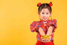 快乐亚洲中国人女孩微笑穿红色的旗袍持有黄金锭